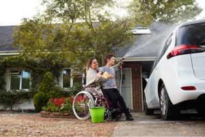 woman in wheelchair washing car with son